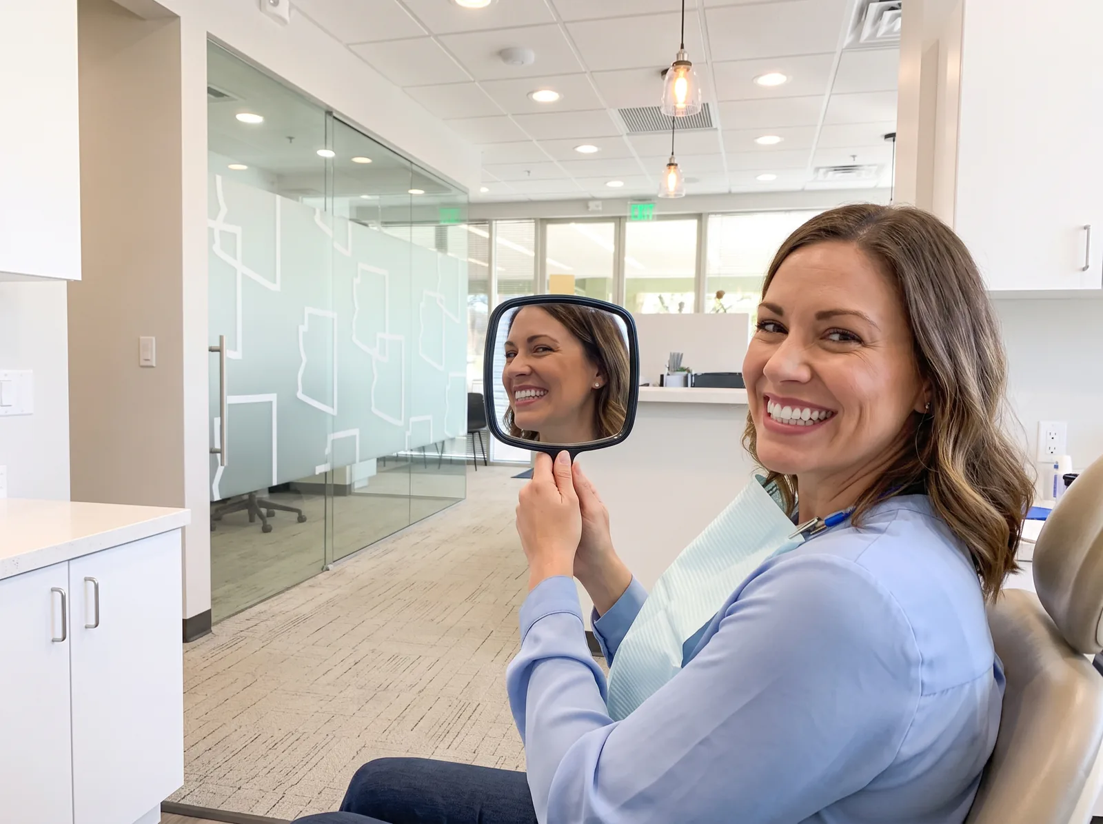 Patient admiring her smile in a hand mirror at Arizona Biltmore Dentistry in Phoenix